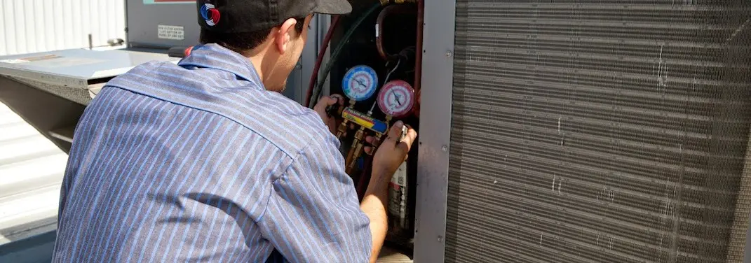 HVAC technician servicing a condenser unit in Antis